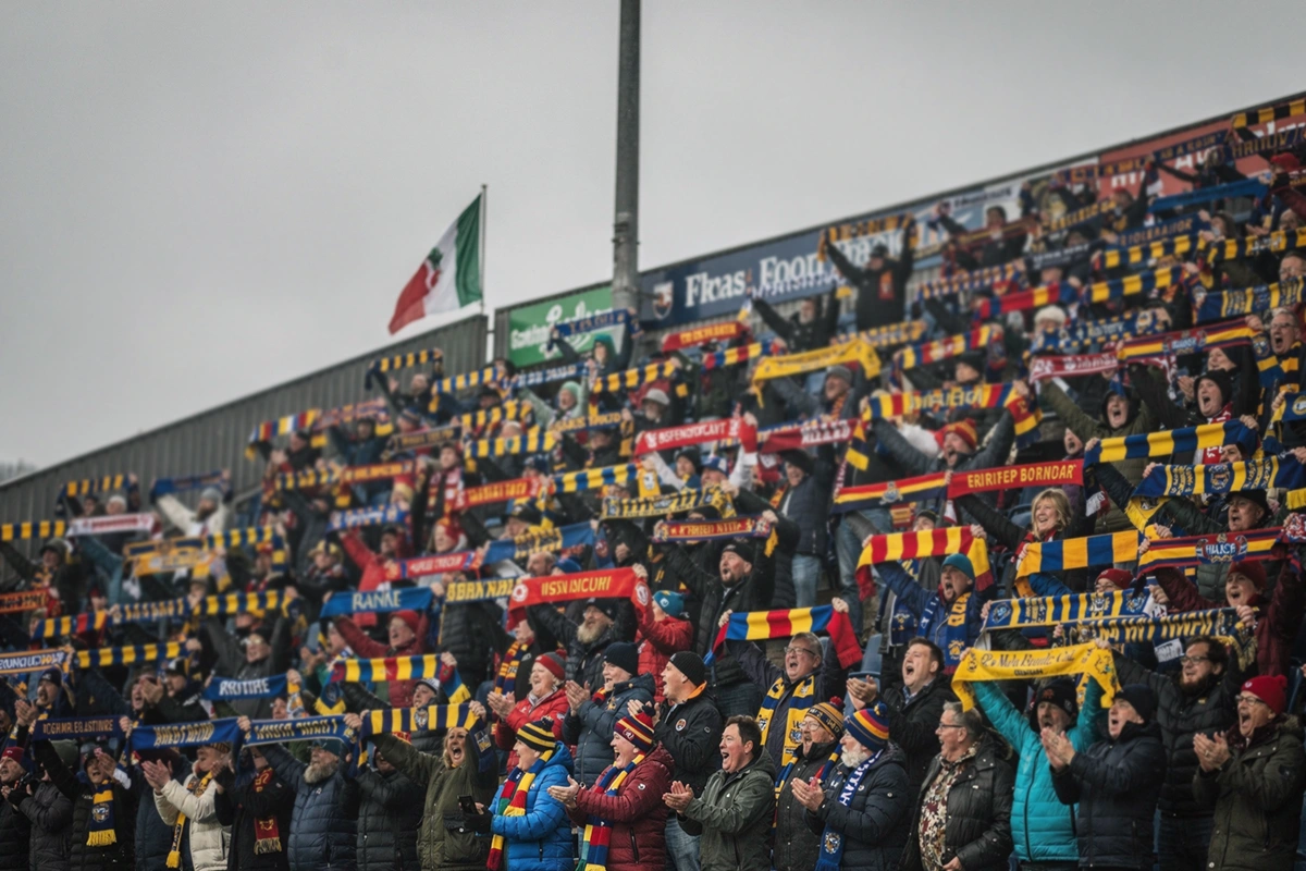Estadio inglés lleno de aficionados con bufandas de colores del equipo local